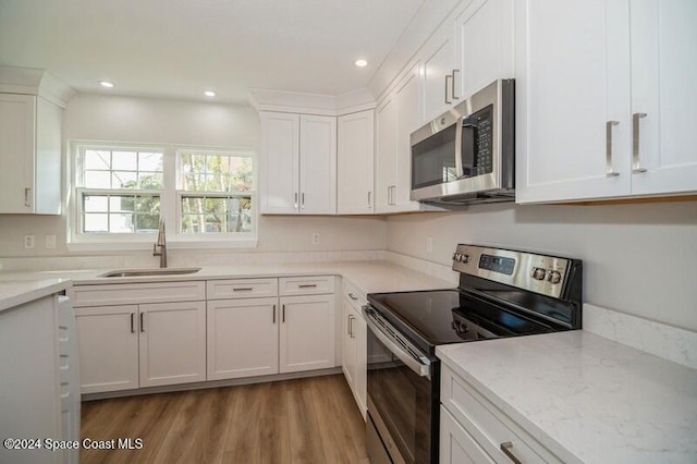 kitchen featuring white cabinets, light wood-type flooring, stainless steel appliances, and sink