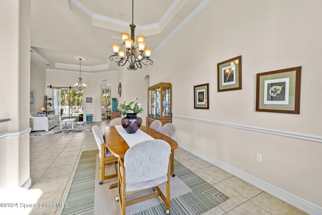 dining space with a chandelier, light tile patterned floors, a tray ceiling, and ornamental molding