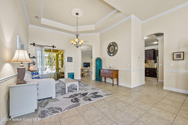 living room featuring a chandelier, a tray ceiling, ornamental molding, and light tile patterned flooring