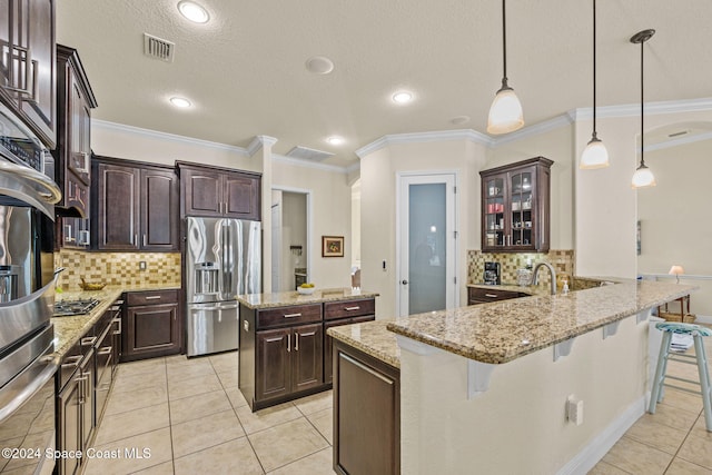 kitchen featuring kitchen peninsula, decorative light fixtures, a breakfast bar area, dark brown cabinets, and appliances with stainless steel finishes