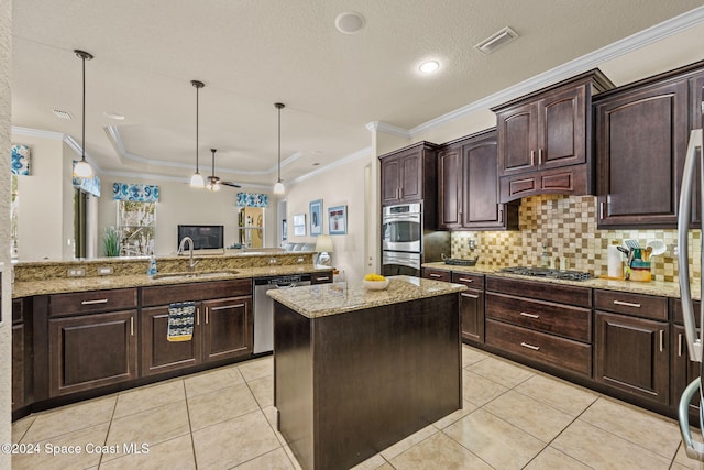 kitchen featuring dark brown cabinetry, sink, stainless steel appliances, decorative light fixtures, and a kitchen island