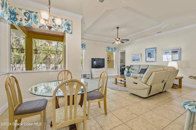 tiled dining room with a tray ceiling, ceiling fan with notable chandelier, and ornamental molding