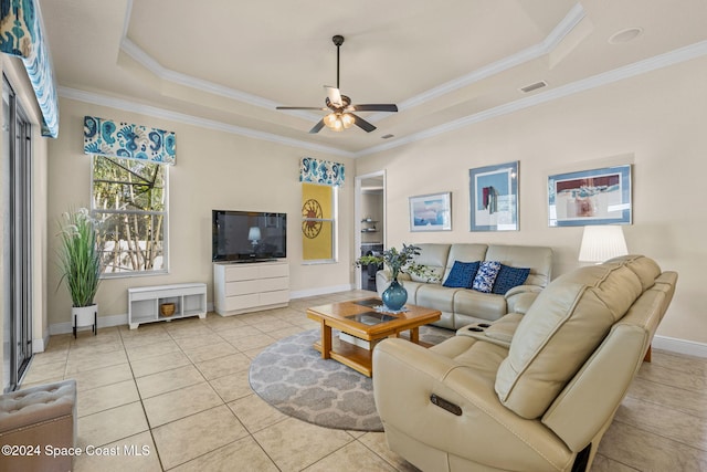 tiled living room featuring a raised ceiling, ceiling fan, and ornamental molding