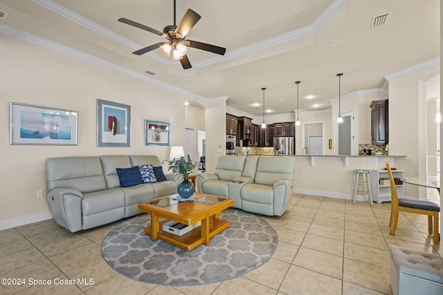 tiled living room with a raised ceiling, ceiling fan, and crown molding