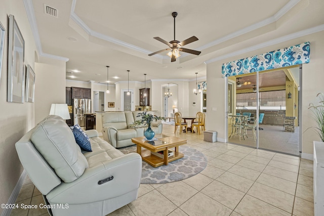 tiled living room featuring ceiling fan with notable chandelier, crown molding, and a tray ceiling