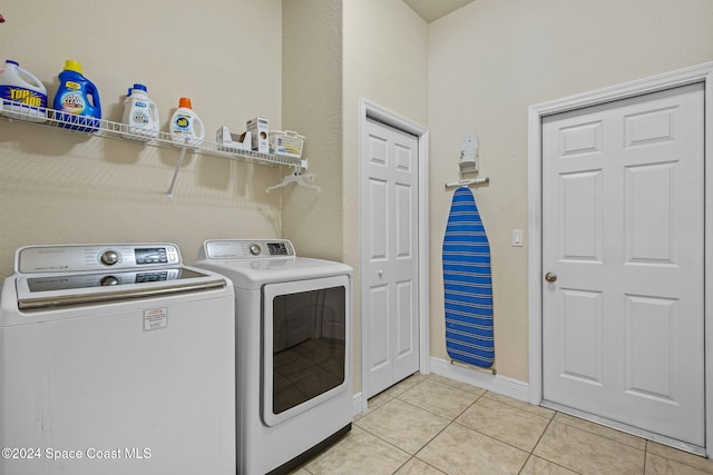 clothes washing area featuring light tile patterned floors and washer and clothes dryer