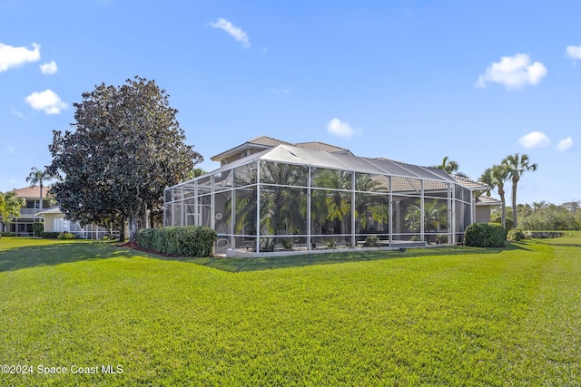 back of house with a lanai and a lawn