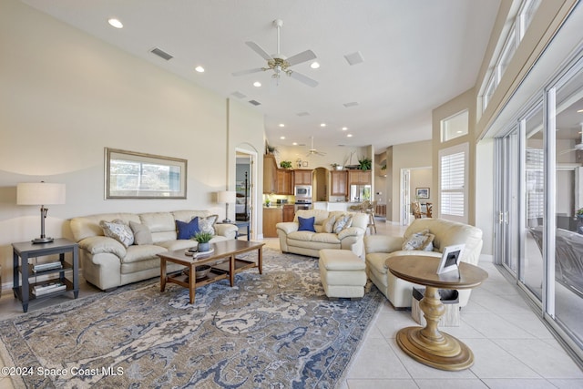 tiled living room featuring plenty of natural light, ceiling fan, and a towering ceiling