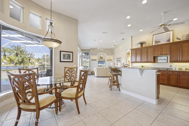 dining room featuring ceiling fan, light tile patterned floors, and a high ceiling