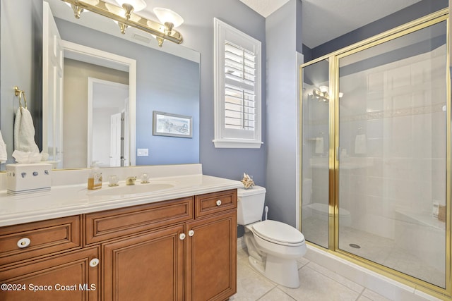 bathroom featuring tile patterned flooring, vanity, toilet, and a shower with shower door