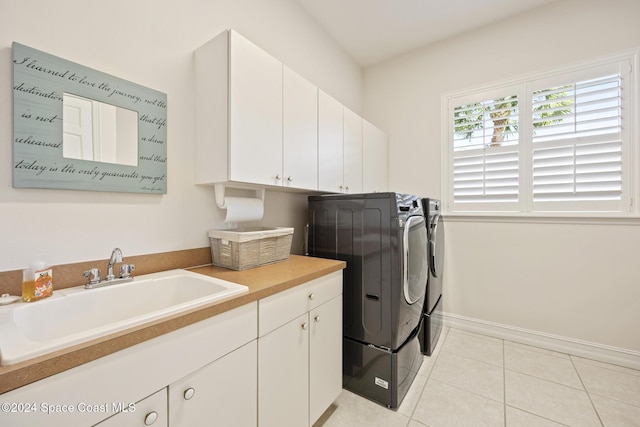 clothes washing area featuring washer and clothes dryer, cabinets, light tile patterned floors, and sink