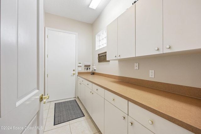 kitchen with light tile patterned floors and white cabinetry