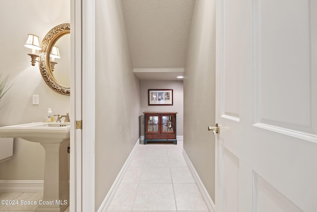 hall with sink, light tile patterned floors, and a textured ceiling