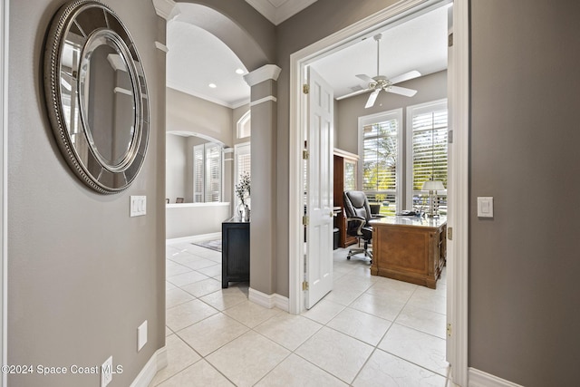 hallway with decorative columns, ornamental molding, and light tile patterned flooring