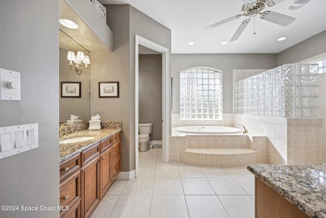 bathroom featuring vanity, ceiling fan with notable chandelier, tiled tub, tile patterned flooring, and toilet