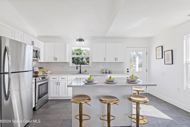 kitchen with white cabinets, appliances with stainless steel finishes, a center island, and a wealth of natural light