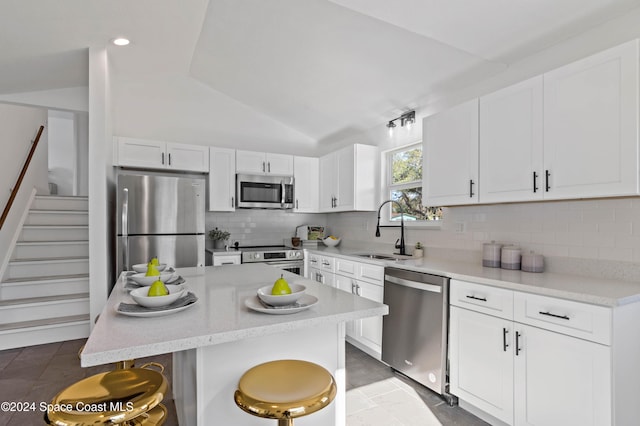 kitchen with a center island, sink, appliances with stainless steel finishes, and vaulted ceiling