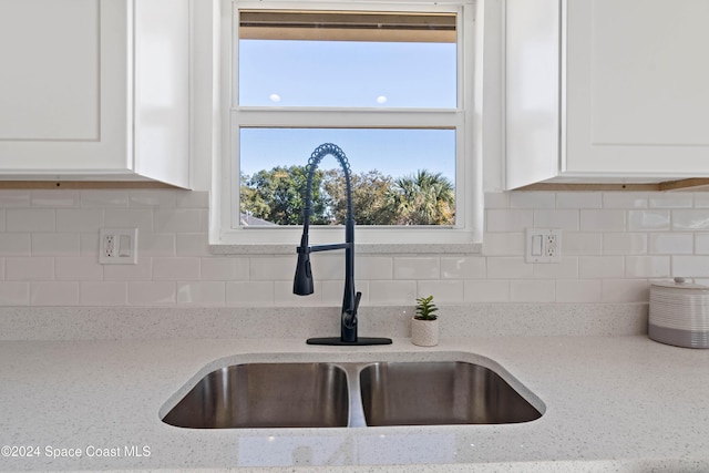 details with decorative backsplash, light stone counters, sink, and white cabinets