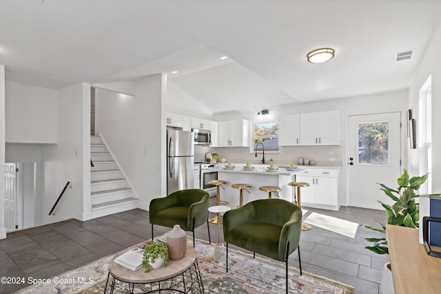 living room featuring dark tile patterned flooring, vaulted ceiling, and sink