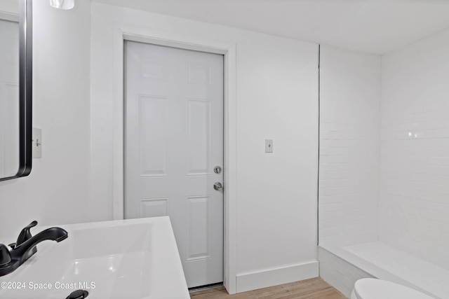 bathroom with toilet, a shower, hardwood / wood-style floors, and sink