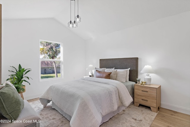 bedroom with light hardwood / wood-style floors and lofted ceiling