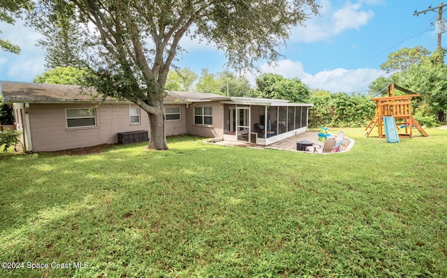 back of property with a playground, a sunroom, a lawn, and a patio