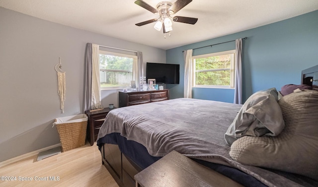 bedroom with ceiling fan, light wood-type flooring, and multiple windows