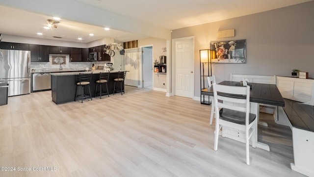 kitchen with appliances with stainless steel finishes, backsplash, a breakfast bar, a center island, and light hardwood / wood-style floors