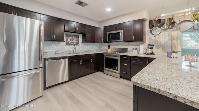 kitchen featuring backsplash, sink, dark brown cabinets, light hardwood / wood-style floors, and stainless steel appliances