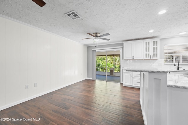 kitchen featuring ceiling fan, light stone counters, tasteful backsplash, dark hardwood / wood-style flooring, and white cabinetry