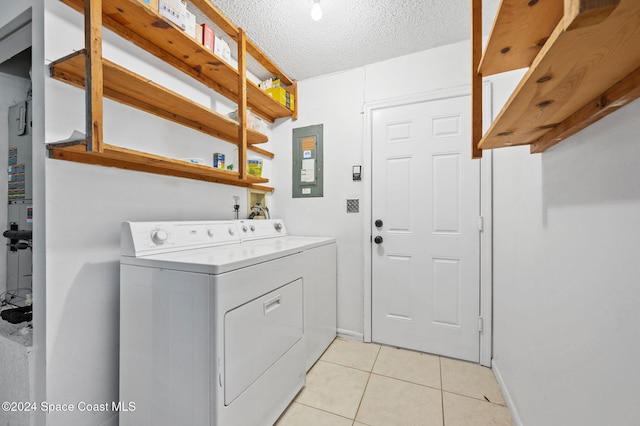 laundry area featuring washer and dryer, a textured ceiling, electric panel, and light tile patterned flooring