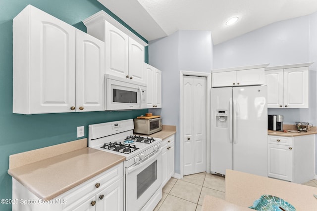 kitchen featuring white appliances, white cabinets, light tile patterned flooring, and lofted ceiling