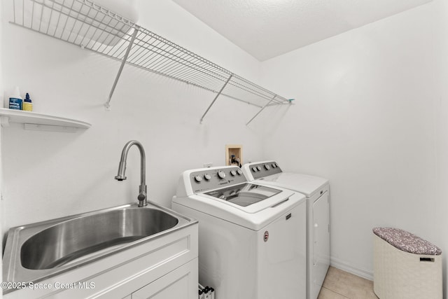 laundry room with sink, a textured ceiling, washing machine and clothes dryer, and light tile patterned floors