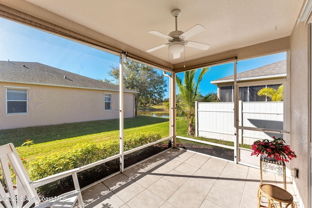 unfurnished sunroom with ceiling fan and a water view