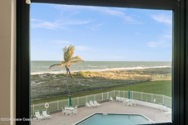 view of pool featuring a water view, a patio, and a view of the beach