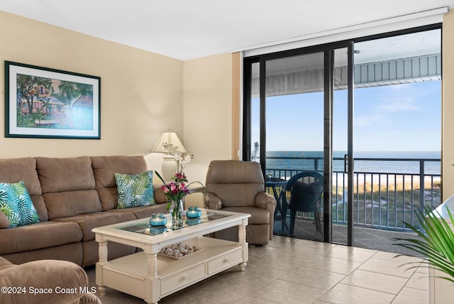 living room featuring a water view, a wall of windows, and light tile patterned floors