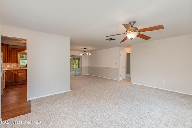 unfurnished living room featuring ceiling fan with notable chandelier and light colored carpet