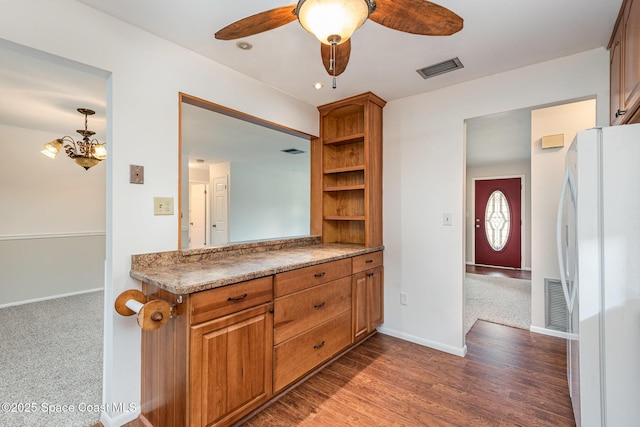 kitchen with ceiling fan with notable chandelier, white refrigerator, kitchen peninsula, and dark wood-type flooring