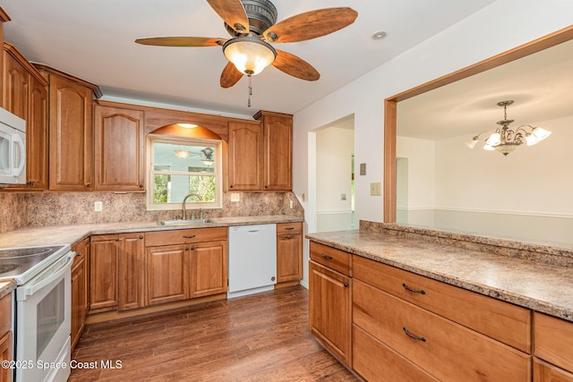 kitchen with sink, dark wood-type flooring, white appliances, decorative backsplash, and ceiling fan with notable chandelier