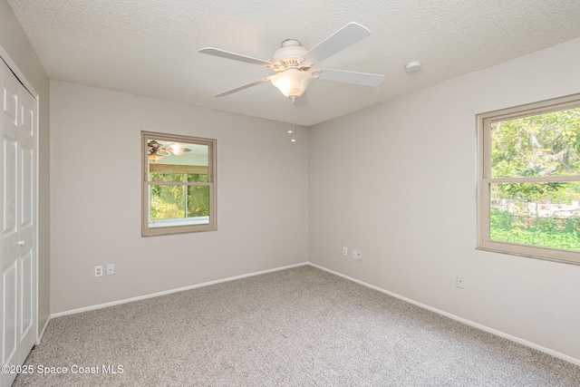 spare room with a textured ceiling, carpet floors, and ceiling fan