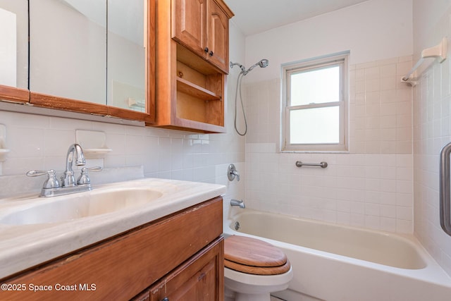 full bathroom with vanity, backsplash, tiled shower / bath combo, toilet, and tile walls