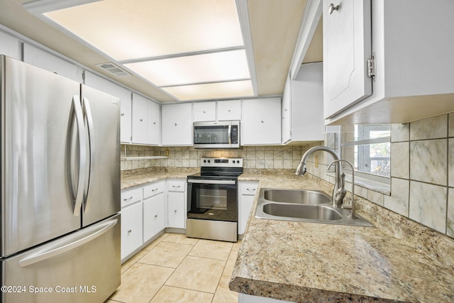 kitchen with sink, light tile patterned floors, tasteful backsplash, white cabinets, and appliances with stainless steel finishes