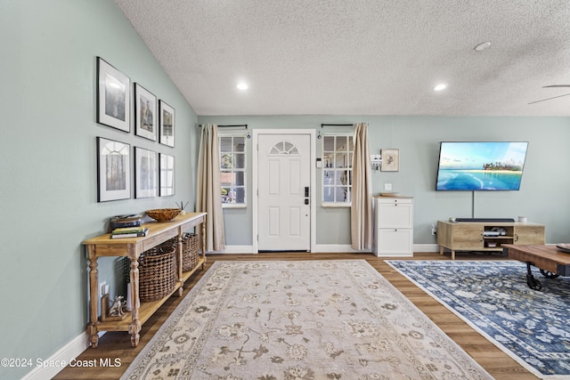 foyer featuring hardwood / wood-style floors, ceiling fan, lofted ceiling, and a textured ceiling