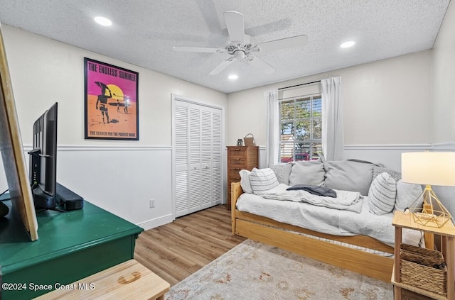 bedroom featuring hardwood / wood-style floors, a textured ceiling, a closet, and ceiling fan