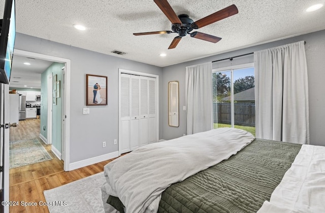 bedroom featuring access to outside, ceiling fan, a textured ceiling, light hardwood / wood-style floors, and a closet