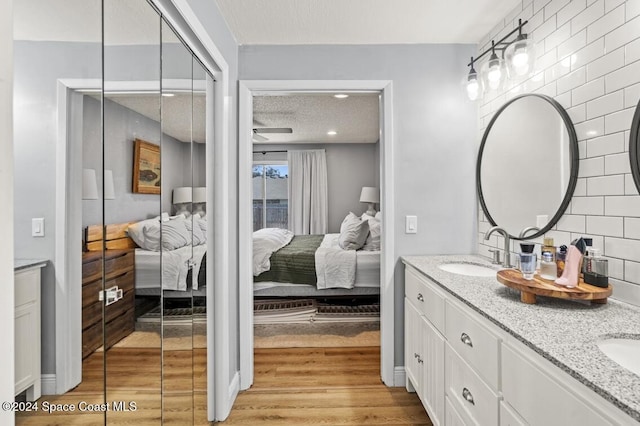 bathroom featuring ceiling fan, backsplash, a textured ceiling, vanity, and hardwood / wood-style flooring