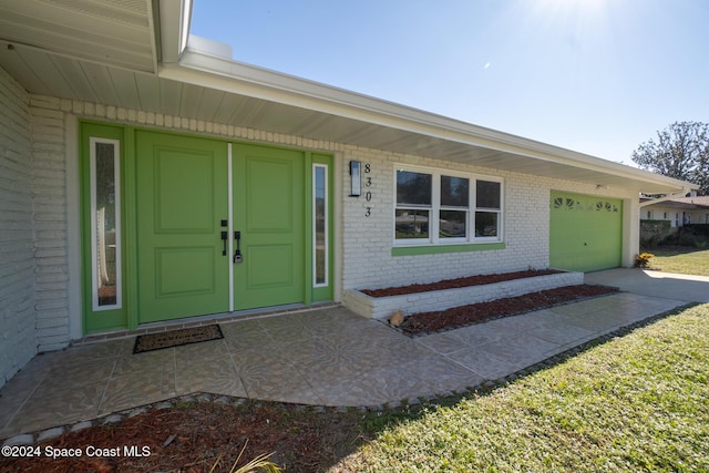 8303 Sylvan Dr, Melbourne, FL 32904 - entrance to property featuring brick siding, a garage, and driveway