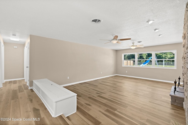 unfurnished living room with ceiling fan, a textured ceiling, and light wood-type flooring