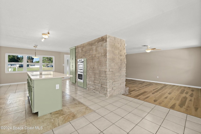 kitchen with green cabinets, light hardwood / wood-style flooring, black electric cooktop, decorative light fixtures, and a kitchen island