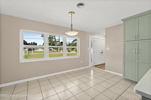 unfurnished dining area with light tile patterned flooring and a textured ceiling